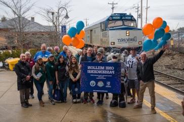 Train No. 684 arrives behind a group celebrating the 1 million rider milestone