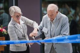 Man and woman cut a ribbon with giant scissors